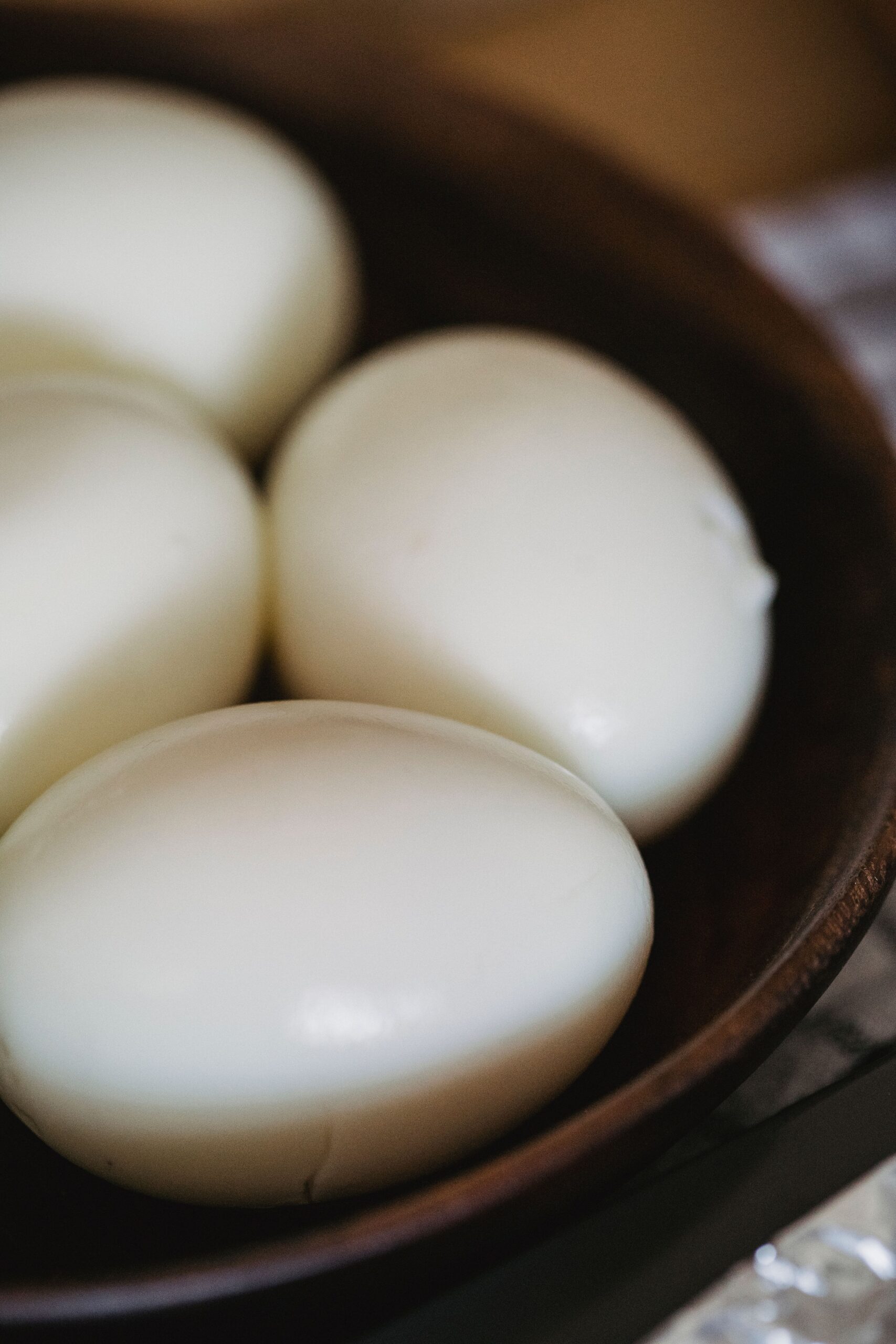 Close-up view of boiled eggs in a rustic wooden bowl