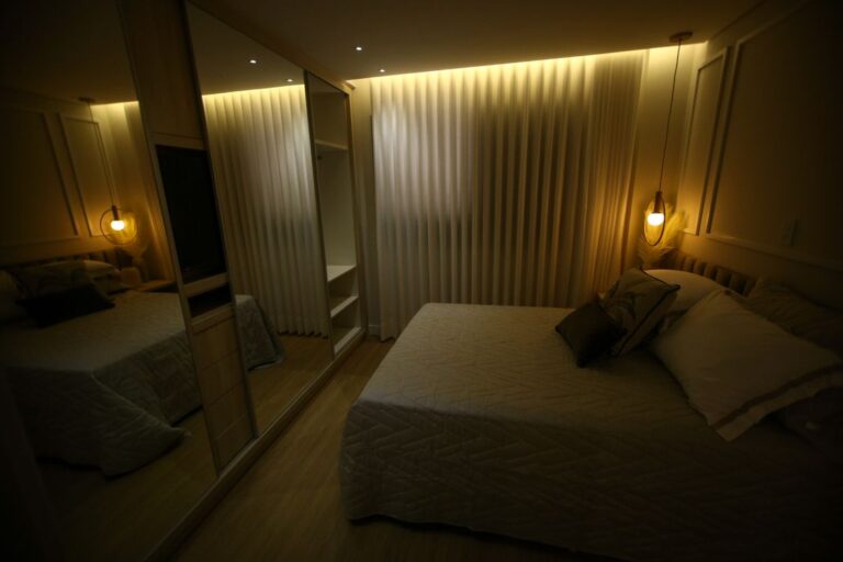 Calm dark bedroom with a neatly made bed and warm low light, set up for sleeping better at night naturally