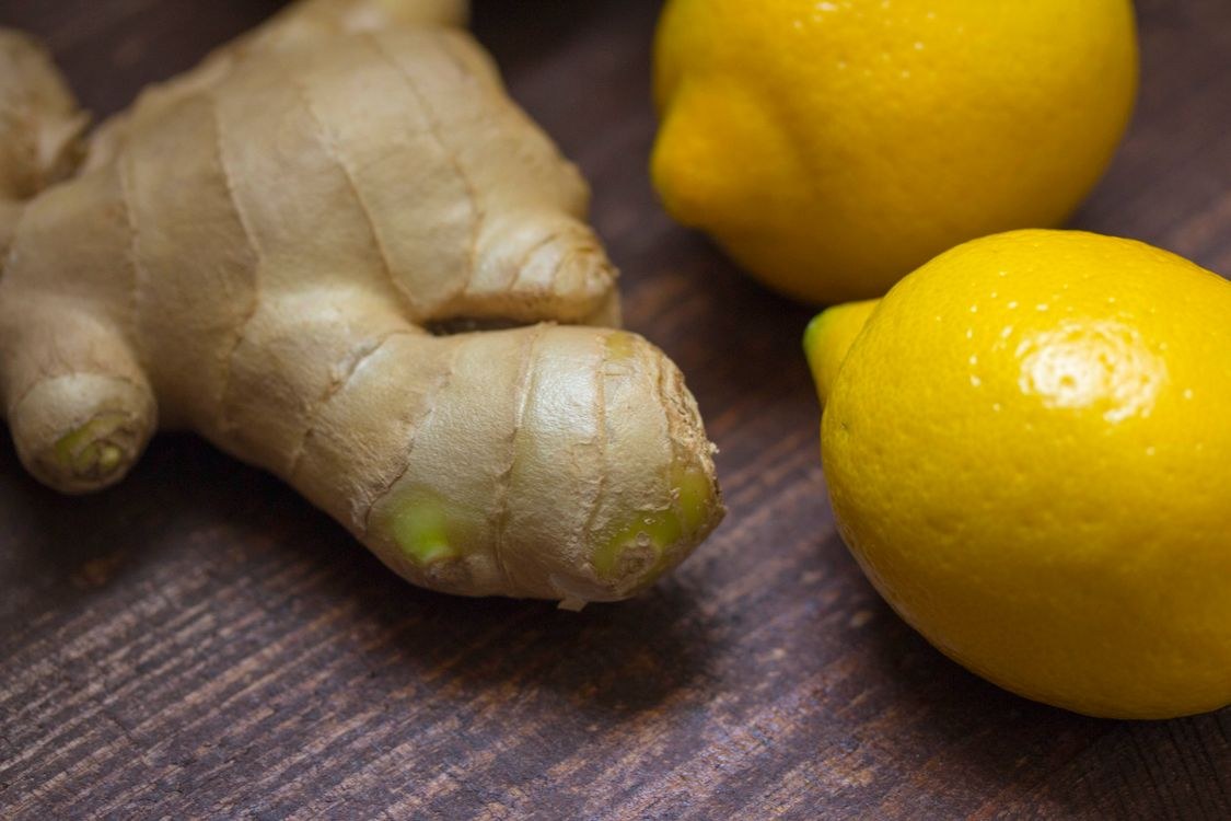 Lemon, ginger and mint next to a mug of warm water as natural flavor add ins