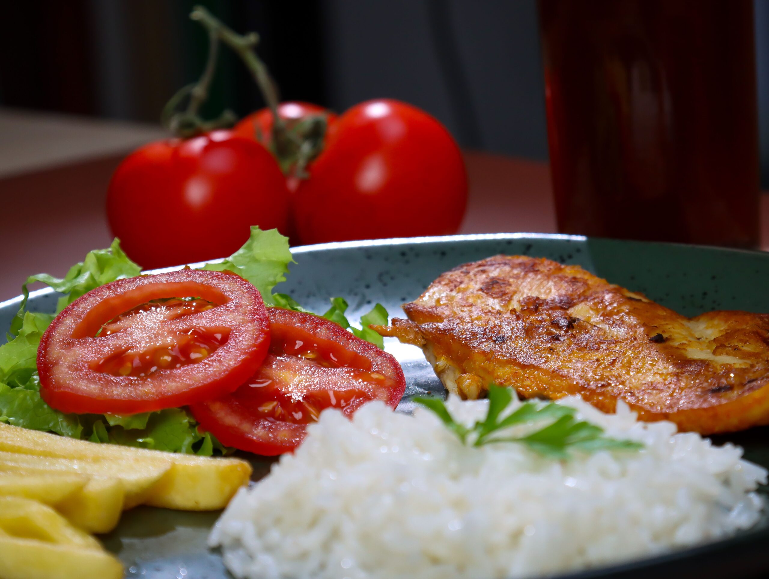 A plate of grilled chicken with rice and fresh vegetables