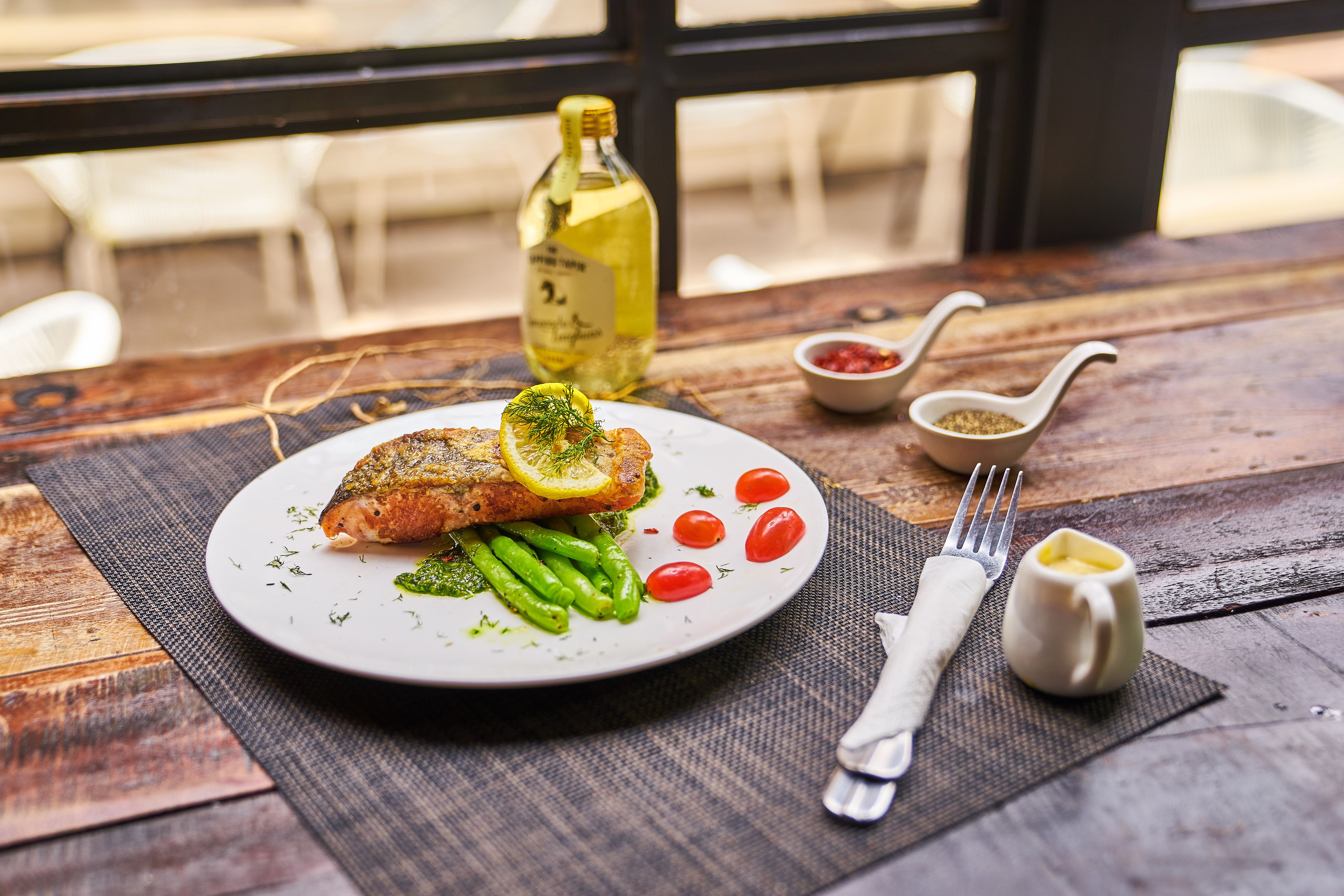 Grilled salmon meal with lemon, tomatoes, and asparagus on a rustic wooden table