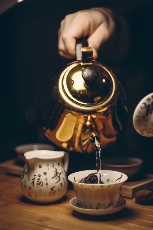 Kettle pouring hot water into a mug that is left to cool to a safe sipping temperature
