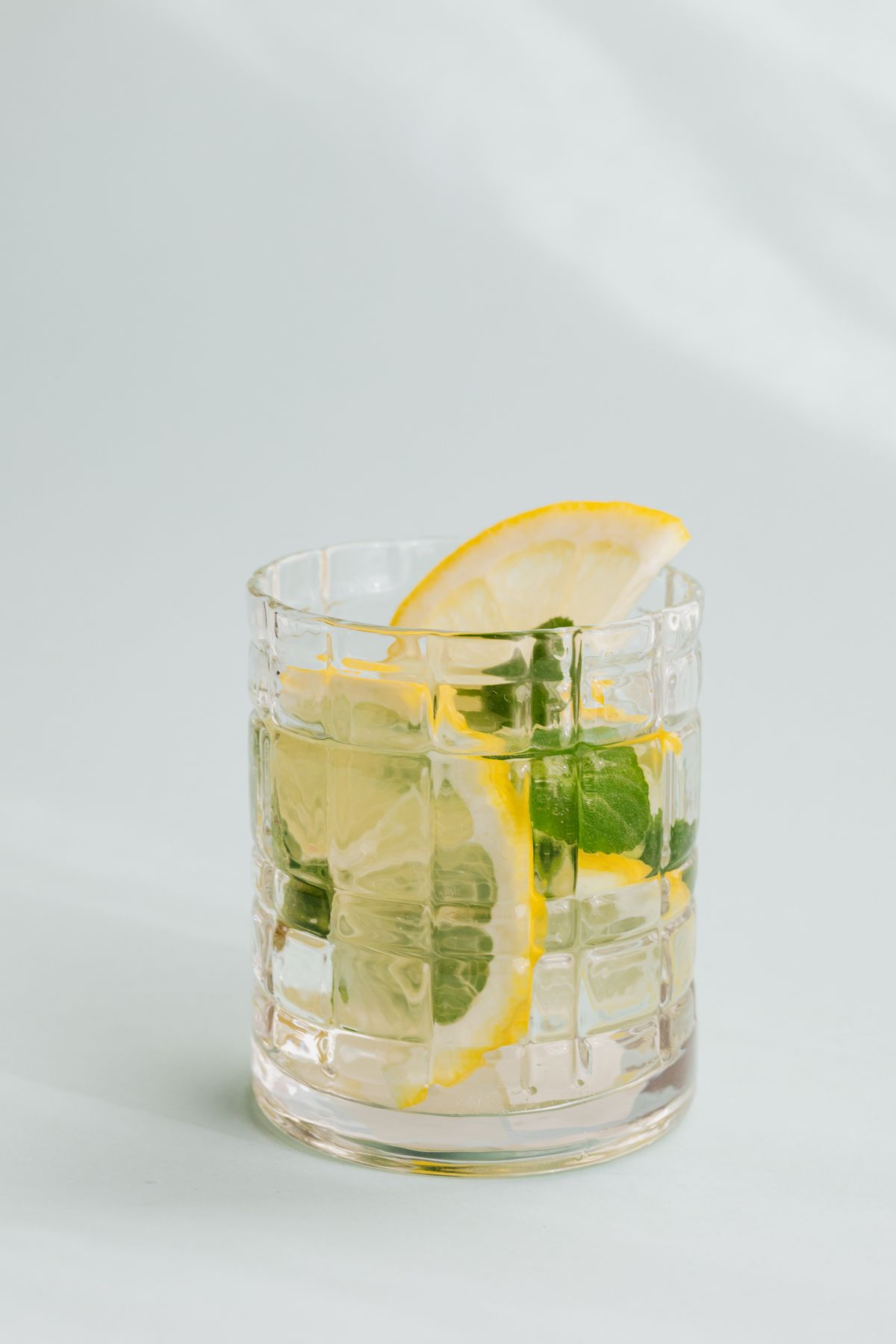Glass of lemon water with lemon slices and fresh mint leaves