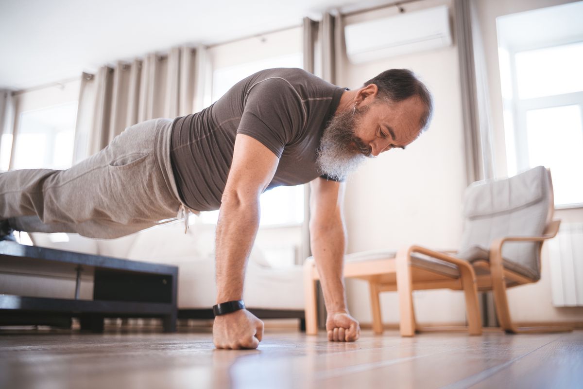 Older man doing a push-up on his living room floor