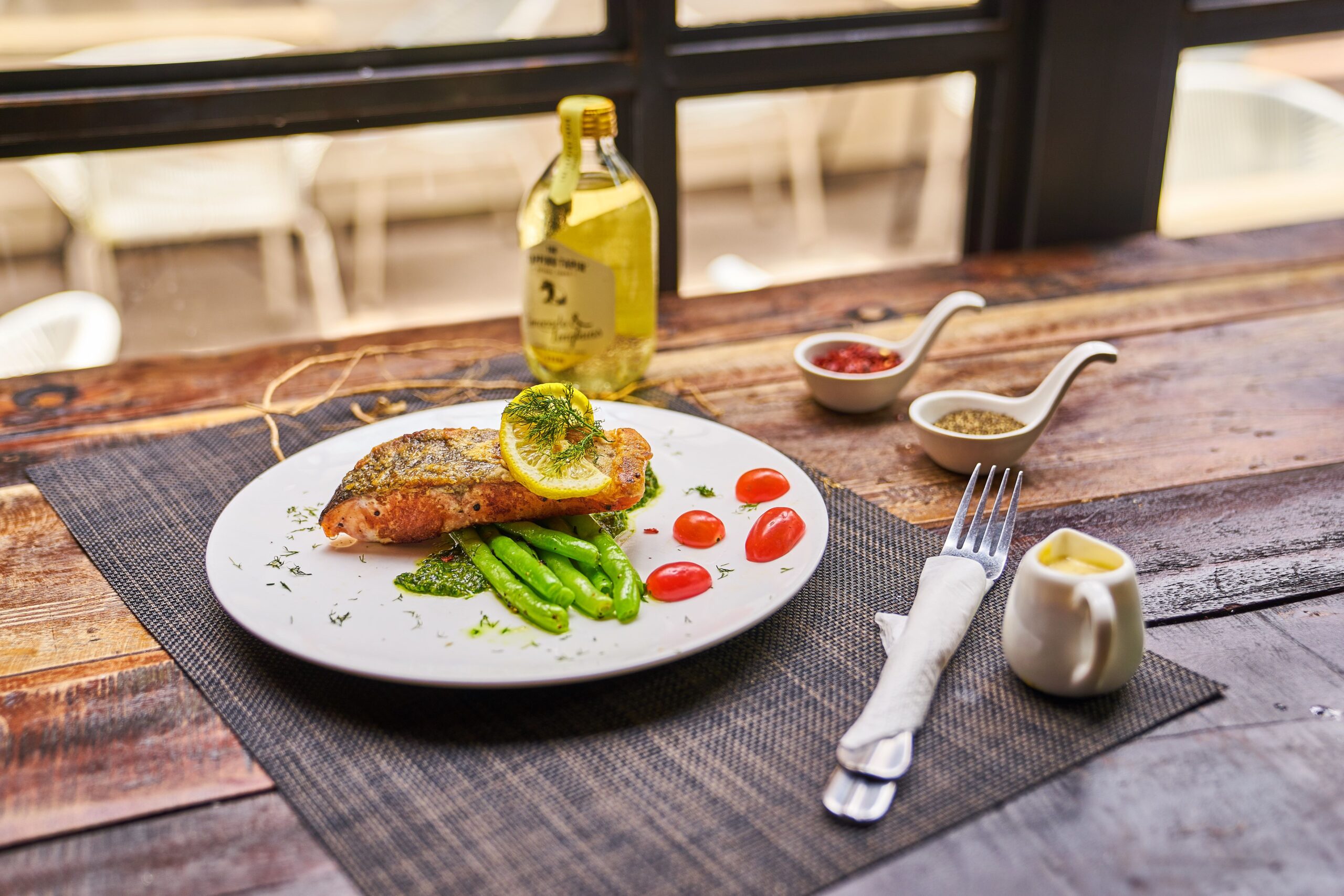 Grilled salmon meal with lemon, tomatoes, and asparagus on a rustic wooden table