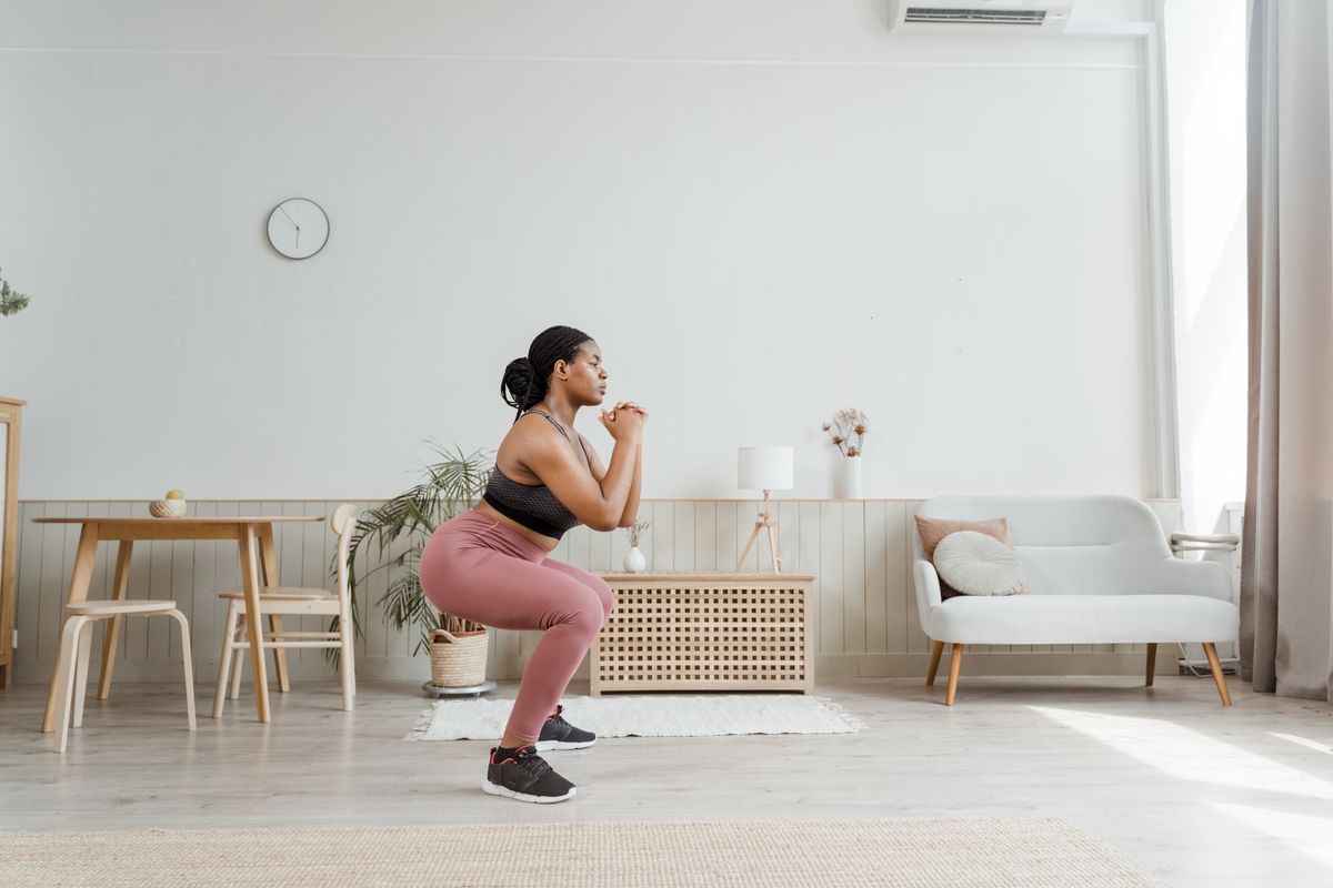 Woman doing a bodyweight squat with good form in a bright living room