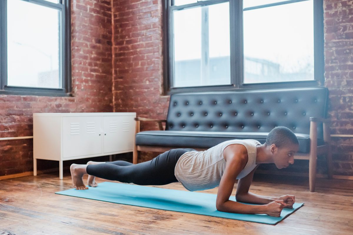 Woman holding a forearm plank on a mat at home