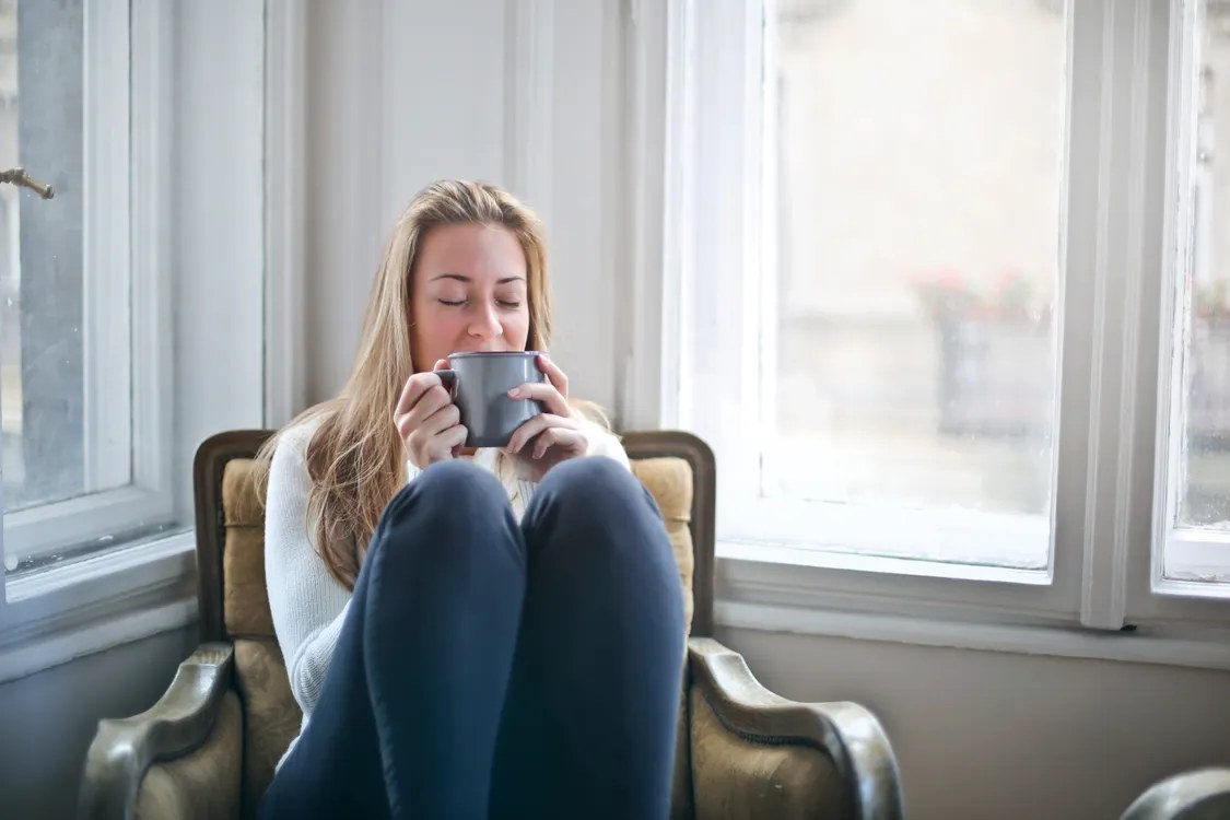 Person holding a warm mug near a window during a calm morning breakfast