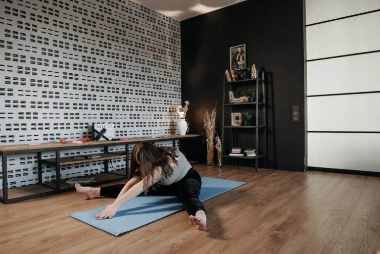Woman doing a pilates mat workout at home on a mat in a bright living room