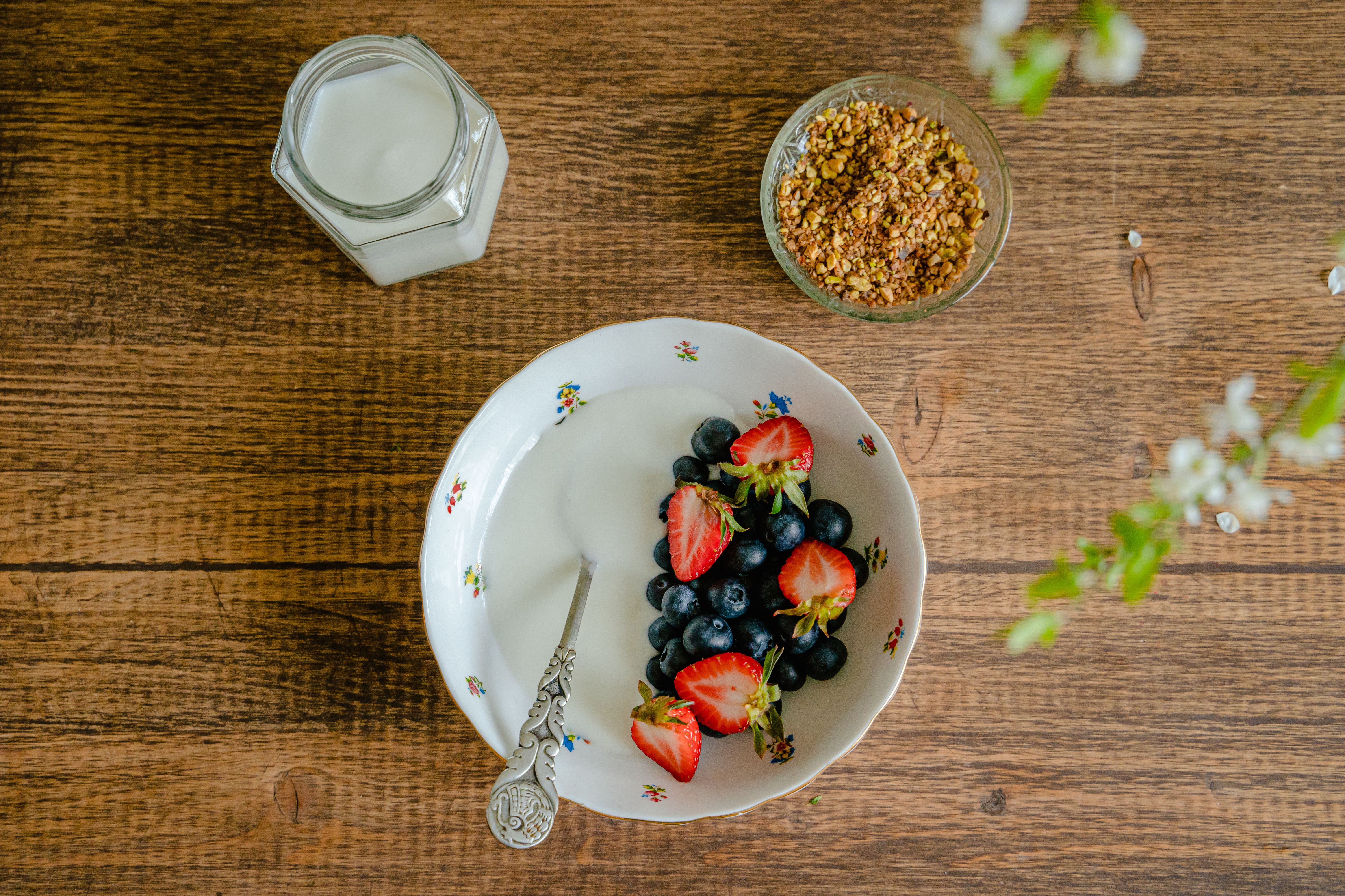 Bowl of yogurt with fresh strawberries, blueberries, and granola on a wooden table
